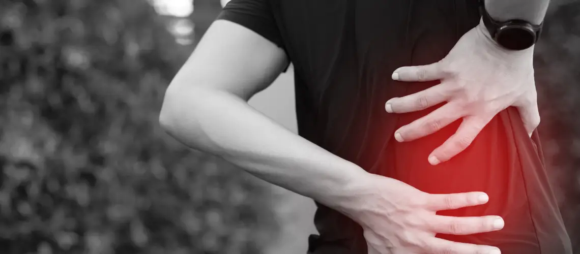 Person holding lower back in pain next to weed-based products